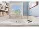 Relaxing soaking tub with a window view and built-in shelving for linens and toiletries at 1112 Sutton Dr, Mcdonough, GA 30252
