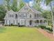 Charming two-story home features a spacious porch, manicured lawn and beautiful, mature trees at 1245 Smokehouse Trl, Cumming, GA 30041