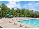 Relaxing community pool area with lounge chairs, umbrellas, and a slide surrounded by mature trees at 2965 Westlington Cir, Cumming, GA 30040