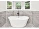 This updated bathroom with natural light features a luxurious soaking tub and marble tile at 3233 Glynn Mill Dr, Snellville, GA 30039