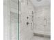 Close up of a marble tiled shower with built-in bench, and a glass door and shower-head at 1645 Oakfield Ln, Roswell, GA 30075