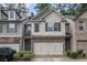 Charming townhome with a two-car garage, neutral siding, stone accents, and manicured landscaping at 2294 Spicy Pine Ln, Lawrenceville, GA 30044