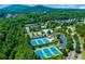 Aerial view of blue and green tennis courts surrounded by verdant trees at 608 Chickory Ct, Woodstock, GA 30188