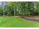 A backyard featuring lush green grass, mature trees, and a gravel pathway leading to a firepit at 1340 Gran Forest Dr, Cumming, GA 30041