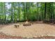 Stone firepit with rock benches surrounded by pea gravel and mature trees at 1340 Gran Forest Dr, Cumming, GA 30041
