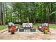 An outdoor patio setting featuring cushioned seating, a coffee table, and decorative plants against a wooded backdrop at 1340 Gran Forest Dr, Cumming, GA 30041