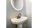 Clean, minimalist bathroom with a pedestal sink and round mirror offering a simple design at 4424 English Loop, Stonecrest, GA 30038