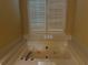 A large white bathtub with jets situated beneath a large shuttered window at 512 Ollas Walk, Mcdonough, GA 30252