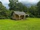 Outbuilding situated in an expansive green lawn, surrounded by mature trees at 512 Ollas Walk, Mcdonough, GA 30252