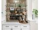 Close up of custom bar featuring marble countertop, sleek white cabinets, and decorative mirrored backsplash at 5968 Reddington Way, Sandy Springs, GA 30328