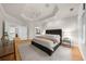 Spacious bedroom with a tray ceiling, hardwood floors, a serene ambiance, and access to an ensuite bathroom at 5968 Reddington Way, Sandy Springs, GA 30328