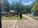 Backyard view featuring a wooden deck, grass, and a wooden path to a fire pit area at 6701 Knollwood Cir, Douglasville, GA 30135