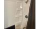Tub with a shower featuring built-in shelving and white tile at 6701 Knollwood Cir, Douglasville, GA 30135