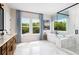Luxurious bathroom featuring a soaking tub, glass shower, double vanity, and scenic outdoor views at 1572 Wicker Wood Se Pl, Smyrna, GA 30080