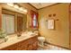 Well-lit bathroom featuring a vanity with a single sink, toilet, and window with red curtains at 3452 Monica Lane Southwest Sw Ln, Conyers, GA 30094
