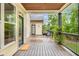 View of a covered back porch with wooden floors, railings, columns, and a door leading to the backyard at 374 Beaumont Farms Dr, Sharpsburg, GA 30277