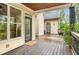Covered back porch with wooden floors, black railings and columns, plants, and views of the backyard at 374 Beaumont Farms Dr, Sharpsburg, GA 30277