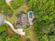 An aerial view reveals the home's pool, surrounding trees, an outdoor seating area, and winding driveway at 325 Edwards Brook Ln, Canton, GA 30115
