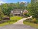 A charming two-story brick home features a manicured front lawn, black fencing, and a circular driveway at 325 Edwards Brook Ln, Canton, GA 30115