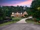 Stately brick home with lush landscaping, circle driveway, and mature trees at dusk at 325 Edwards Brook Ln, Canton, GA 30115