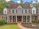 A beautiful two-story brick home has a long front porch with white columns, seating, and a brick walkway at 325 Edwards Brook Ln, Canton, GA 30115