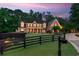 A brick two-story home has a manicured front yard with a black fence, plus a long driveway at dusk at 325 Edwards Brook Ln, Canton, GA 30115