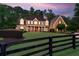 A brick two-story home has a manicured front yard with a black fence, plus a long driveway at dusk at 325 Edwards Brook Ln, Canton, GA 30115