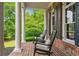 Charming front porch with brick flooring, white columns, and comfortable rocking chairs at 325 Edwards Brook Ln, Canton, GA 30115