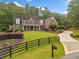 A beautiful two-story brick home boasts a manicured front yard, black fencing, and a circular driveway at 325 Edwards Brook Ln, Canton, GA 30115
