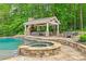 Beautiful outdoor pool and hot tub, along with a covered outdoor living area and a spacious patio, perfect for entertaining at 325 Edwards Brook Ln, Canton, GA 30115