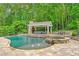 Swimming pool with water feature near a covered lounge area with stone fireplace and comfortable seating at 325 Edwards Brook Ln, Canton, GA 30115