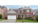 Charming two-story brick home boasts a well-manicured lawn, attached garage, and solar panels at 1489 Belmont Hills Dr, Suwanee, GA 30024