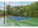 Well-maintained tennis court with green and blue surface surrounded by lush trees at 1489 Belmont Hills Dr, Suwanee, GA 30024
