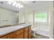 Bright bathroom features a dual sink vanity, soaking tub under a window, and tile flooring at 6561 Squire Pl, Douglasville, GA 30135