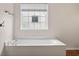 Close up on soaking tub with tile surround and window at 5156 Amberden Hall Dr, Suwanee, GA 30024