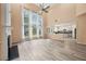 Living room with a fireplace, ceiling fan, and large windows overlooking backyard at 5156 Amberden Hall Dr, Suwanee, GA 30024