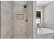Bathroom showing a tiled shower with built-in niche, next to a standalone tub and a window at 8592 Hidden Creek Cir, Snellville, GA 30039