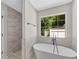 Bright bathroom showcasing a freestanding tub next to a large window and a tiled shower at 8592 Hidden Creek Cir, Snellville, GA 30039