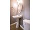 This bathroom features a pedestal sink, oval mirror, and neutral gray walls, offering a simple and functional design at 122 Summer Pl, Norcross, GA 30071