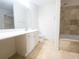 Bright bathroom featuring double sinks, a large mirror, and tiled bath at 200 Renaissance Ne Pkwy # 310, Atlanta, GA 30308