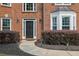 Inviting entryway with a black front door, brick facade, manicured shrubs, and elegant outdoor lighting at 285 Finsbury Park Ct, Suwanee, GA 30024