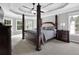 Luxurious main bedroom featuring a four-poster bed, tray ceiling, and large windows at 285 Finsbury Park Ct, Suwanee, GA 30024