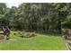 Large backyard featuring a deck, garden area, lush lawn, mature trees, and a chain-link fence at 105 Laney Ct, Mcdonough, GA 30252