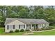 Well-maintained home exterior featuring a front porch, black shutters, and mature trees in a serene setting at 105 Laney Ct, Mcdonough, GA 30252
