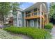 View of condominium exterior featuring wood balconies, a concrete sidewalk, and attractive shrubbery at 202 Berkeley Woods Dr, Duluth, GA 30096