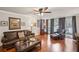 Stylish living room with hardwood floors, leather furniture, and large windows with flowing drapes at 202 Berkeley Woods Dr, Duluth, GA 30096