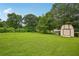 Expansive backyard showcasing lush lawn, mature trees, and a storage shed at 2676 Abington Dr, Snellville, GA 30078