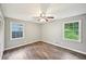 Neutral bedroom with hardwood floors, ceiling fan, and windows facing green space at 2676 Abington Dr, Snellville, GA 30078