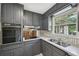 The kitchen has gray painted cabinets, stainless steel appliances, a tile backsplash, and a large window to the outdoors at 2676 Abington Dr, Snellville, GA 30078