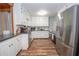 Galley kitchen featuring white cabinets, stainless steel appliances, and hardwood floors at 7505 Rico Rd, Chattahoochee Hills, GA 30268